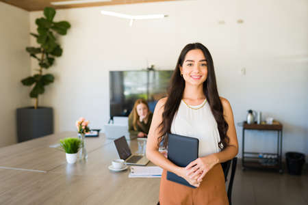 Attractive hispanic woman and boss feeling happy while preparing to give a work presentation at a...