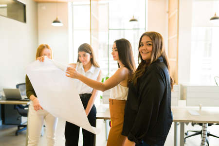 Plus size happy woman and boss smiling while encouraging teamwork with female co-workers at the officeの写真素材