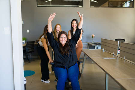 Happy women playing and laughing while having fun at the office and taking a break from working