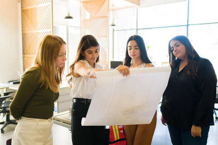 Attractive female architects at the office with a good atmosphere of teamwork working with construction plansの写真素材