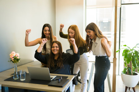 Excited female workteam celebrating and raising her arms after doing a successful business deal and feeling very successfulの写真素材
