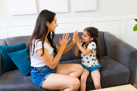 Gorgeous loving mother playing with her little kid and clapping while playing a fun game at home