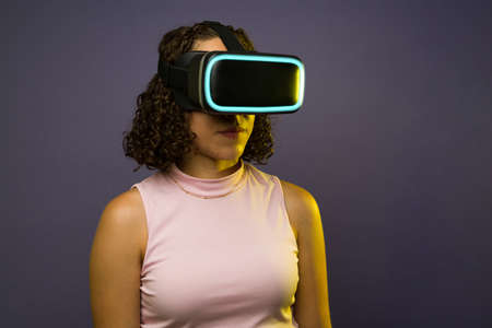 Futuristic young woman with modern VR glasses using immersive virtual simulation technology on the...