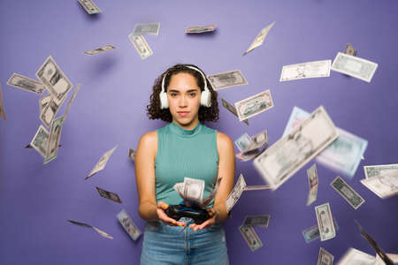 Brunette woman with headphones and a remote control earning a lot of money as a professional female...