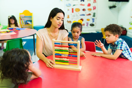 Preschool teacher using an abacus while teaching the numbers and to count to their kindergarten boys and girlsの写真素材
