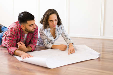 Attractive woman and man lying on the floor and planning the home improvements after moving into a new houseの写真素材