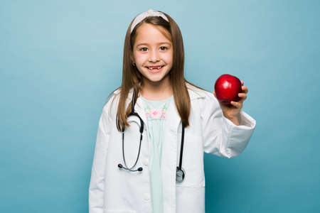 Portrait of an excited little girl aspiring to be a nutritionist holding a healthy apple and smilingの写真素材