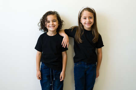 Portrait of two caucasian children friends looking at the camera and posing wearing mockup black...