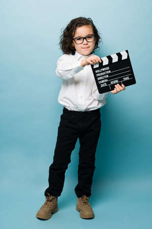 Full length of an adorable little boy using a clapperboard and dreaming to work as a movie director or in entertainmentの写真素材