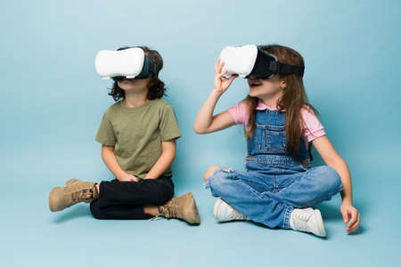 Excited kids smiling wearing VR glasses and watching virtual reality video technology while playing...