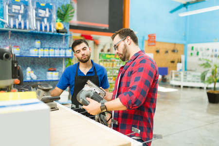 Attractive man customer or carpenter looking to buy a power tool or polisher while taking with the...