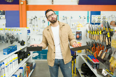 Indecisive stressed man feeling upset and needs help to choose the best brush to buy at the hardware storeの写真素材