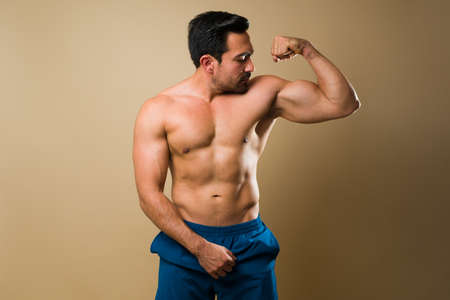 Fitness muscular man doing a bicep curl and showing his arm muscles after his fitness exercises and...
