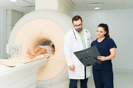 Caucasian doctor and radiologist technician checking the MRI spine resonance of a female patient in the medical imaging labの写真素材