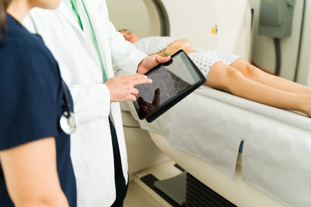 Nurse and doctor looking at the medical results on the tablet of a female patient doing a ct scan test to check for cancerの写真素材