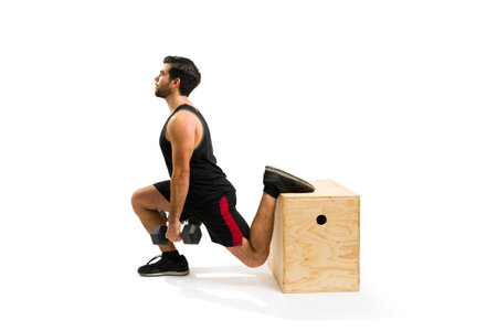 Fitness young man practicing leg lunges using dumbbell weights with a jump box for his cross training workoutの写真素材
