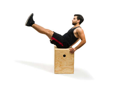 Young man with a fitness healthy lifestyle doing abdominal crunches on top of a jump box during his cross trainingの写真素材