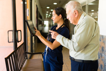 Elderly caucasian old man in his 80s talking with a nurse about his broken hip while staying at the retirement homeの写真素材