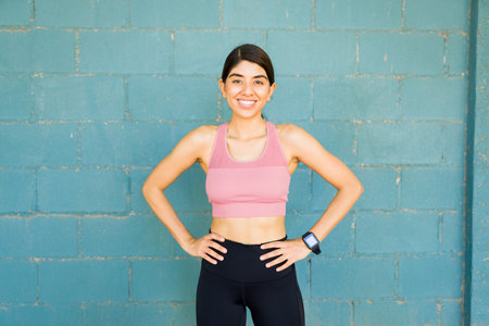 Fit young woman in activewear looking very cheerful while ready to start her workout exercises outdoorsの写真素材