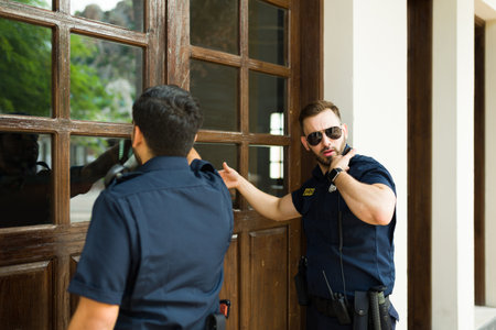 Caucasian male police knocking on the home door with a search warrant to do an investigation and look for criminal evidenceの写真素材
