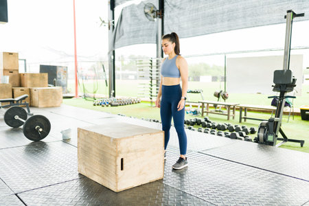 Sporty young woman in activewear preparing to jump on a plyo box and exercising with cross trainingの写真素材