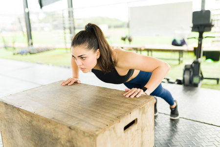 Gorgeous sporty woman doing push up exercises using a plyo box during her cross training routine