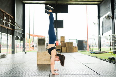Full length of an active young woman doing a headstand and practicing her workout exercises at the...