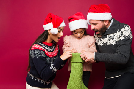 Surprised latin family looking excited and very happy while looking inside the gifts in the christmas stockingの写真素材