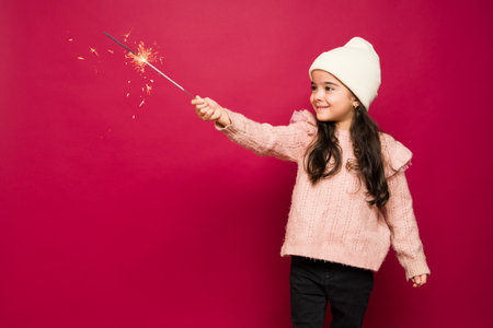 Cheerful latin kid playing with sparklers and having fun while celebrating the christmas holidaysの写真素材