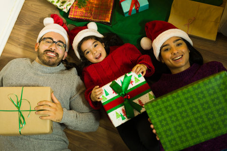 High angle of an excited family with a kid opening presents under the christmas tree during the holidaysの写真素材