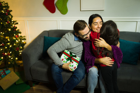 Loving parents hugging their cute child after receiving a surprising gift for the christmas holidays