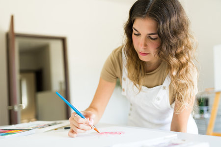 Young creative woman feeling inspired using a paintbrush while painting for her art hobbyの写真素材