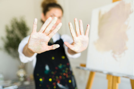 Close up of a young woman showing her hands with paint after finishing a new painting or art workの写真素材