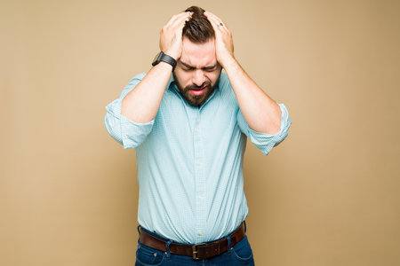 Stressed caucasian man touching his head and suffering from a bad migraine or headache