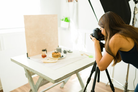 Professional female photographer doing a photo shooting at her studio with camera equipment an lightingの写真素材
