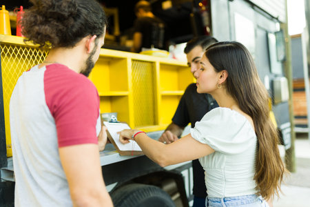 Young woman and friends choosing lunch while looking at the menu from the food truck