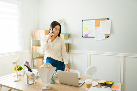 Busy woman entrepreneur talking with a client on the phone while selling jewelry on the online storeの写真素材