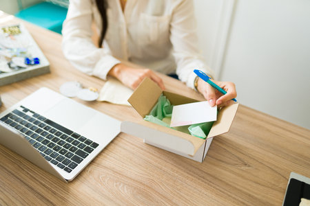 High angle of an entrepreneur putting a thank you note on a package of her online storeの写真素材