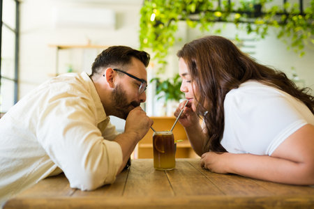 Side view of a romantic couple drinking an iced coffee together with a strawの写真素材