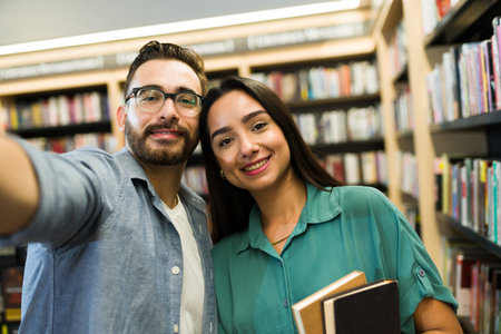 Personal perspective of a cheerful couple of readers taking a selfie for social media while at the book shopの写真素材