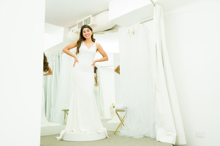 Smiling beautiful young woman buying a wedding dress and looking happy in the dressing roomの写真素材