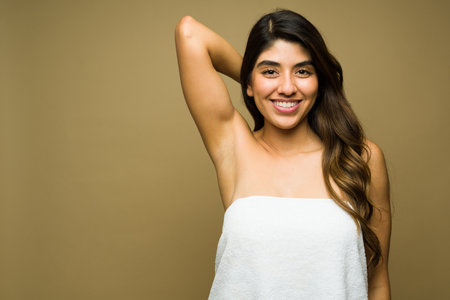 Excited young woman wearing a towel looking happy showing her armpits after doing a hair removal procedure against a background with copy spaceの写真素材