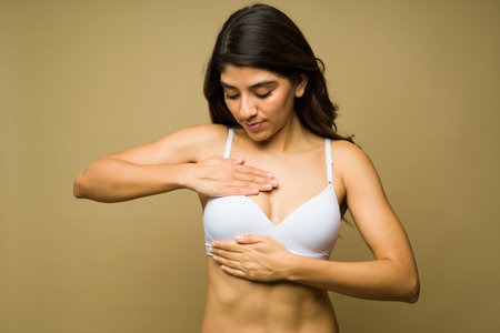 Latin young woman in her 20s wearing a bra doing a self examination to prevent breast cancerの写真素材