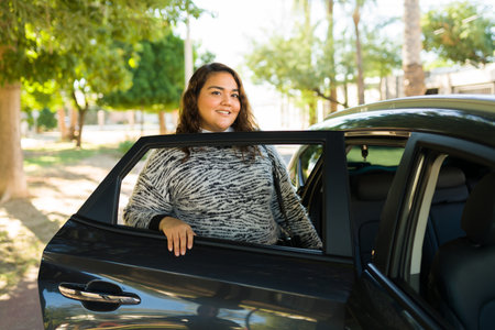 Happy fat woman smiling while getting into the car after requesting a ride from a rideshare service appの写真素材