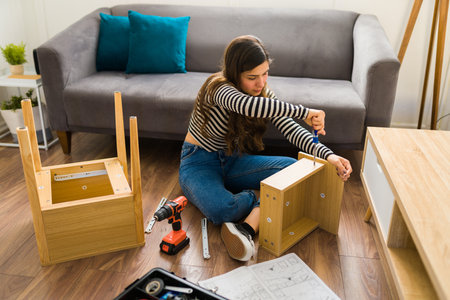 Young woman using a screwdriver to assembly a table and furniture in the living roomの写真素材