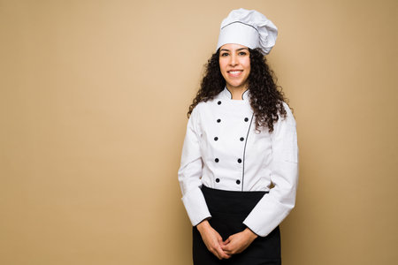 Beautiful happy young woman smiling while working as a chef or cook against a studio background with copy spaceの写真素材