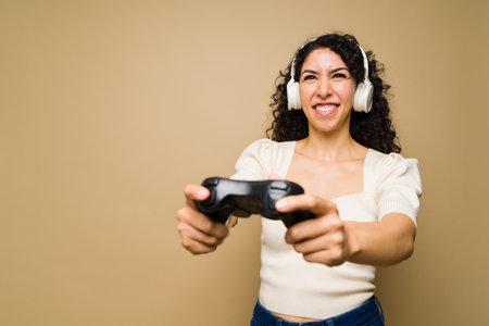 Beautiful excited young woman with headphones playing videogames and having funの写真素材