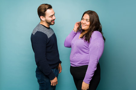 Handsome caucasian man flirting with a beautiful obese woman while asking her out on a dateの写真素材