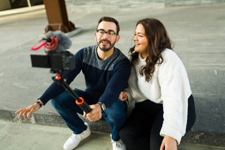 Attractive man and influencer filming a video with his smiling chubby girlfriend to make social...