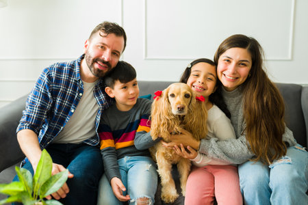 Beautiful happy family with children hugging and resting on the sofa while petting their adorable...
